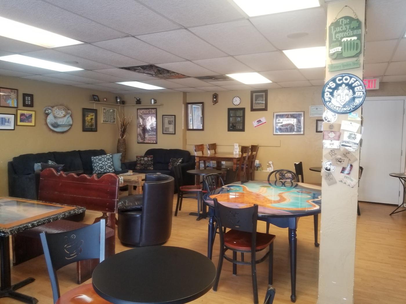 Inside the coffee house: deep couches, mismatched hand painted tables, chairs with a coffee cup cut into the back, and a pillar covered in coffee roaster stickers.